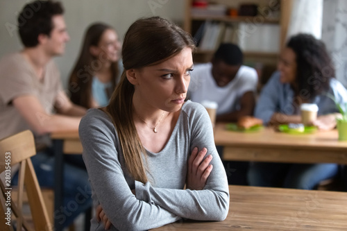 Upset offended by friends young woman sitting alone.