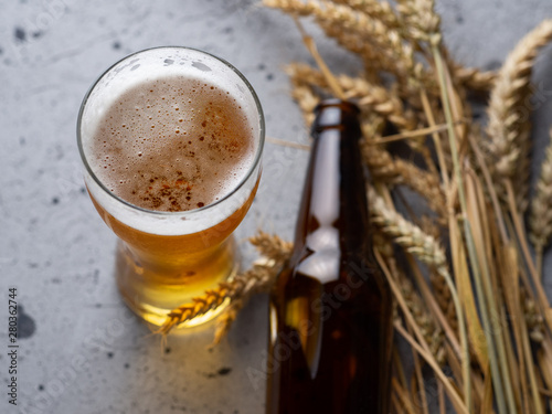 A glass of beer and a beer bottle on the grey stone table top view . Wheat beer