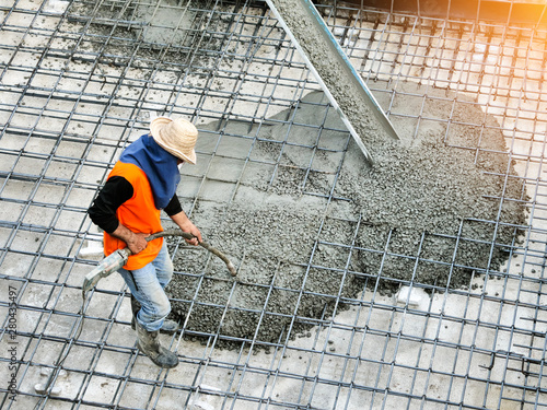 Top view of builders in orange shirt pouring concrete works on the construction site