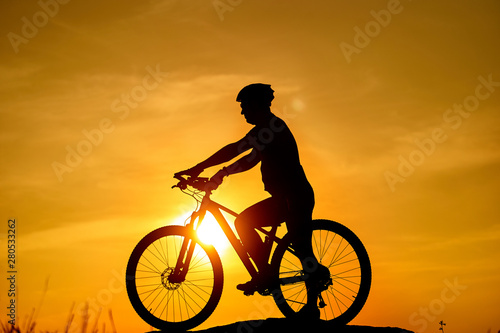 Silhouette of the cyclist riding on a sports bike at sunset. Active Lifestyle Concept.