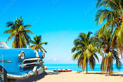 Tropikalna plaża Varadero na Kubie z amerykańskim klasycznym samochodem, żaglówkami i palmami w letni dzień z turkusową wodą. Tło wakacje.