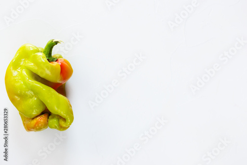 Ugly bell pepper on a wooden board. Ugly food concept, flat lay.