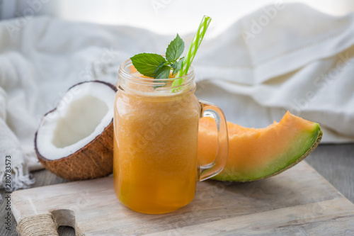 Photo of melon smoothie in jar with straw on light background. Fresh organic Smoothie. Health or detox diet food concept.
