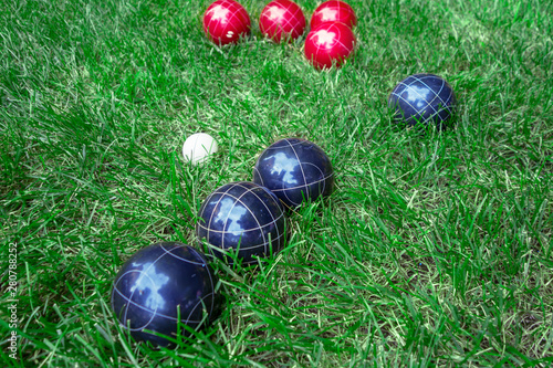 Recreational italian sport whit, red, dark blue bocce balls on a green lawn