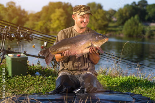 Happy angler with carp fishing trophy