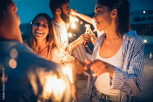 Happy friends with drinks toasting at rooftop party at night