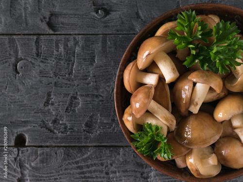 Bowl with fresh mushrooms decorated with parsley on a wooden table. The view from the top.