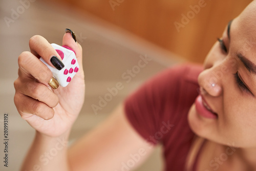 Happy young Asian woman playing with anti-stress fidget cube to get rid of stress