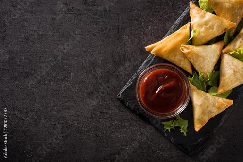 Samsa or samosas with meat and vegetables on black background. Traditional Indian food. Top view. Copyspace