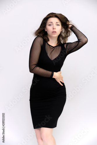 Horizontal Portrait of a pretty slim beautiful fashionable adult girl with beautiful brunette hair in a black dress. It should be in full growth, talking showing different poses and emotions