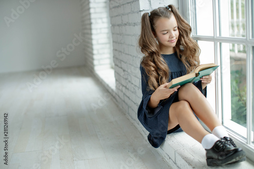 Girl schoolgirl reads a book. School fashion. Fashionable school uniform.