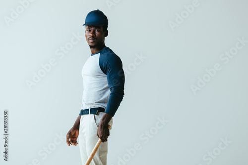 handsome african american baseball player looking at camera isolated on grey