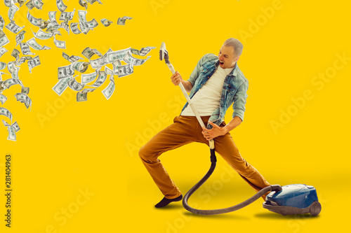 Young man having fun cleaning house with vacuum cleaner man collects money Vacuum