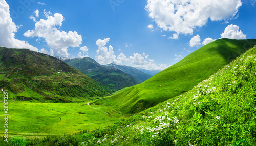 Beautiful green mountain valley. Scenic grassy mountains. Summer day in Georgia. Amazing bright mountain landscape. Green hills and clouds on blue sky