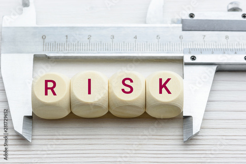 Risk assessment / risk analysis and management concept : Words RISK on wood blocks and a vernier caliper with scales, depict evaluation for financial risk of an investor involved in stock, bond market