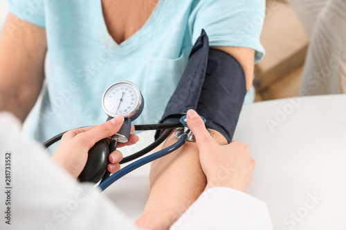 Nurse measuring blood pressure of elderly woman at table, closeup. Assisting senior generation