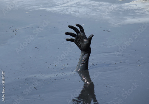 hand of a man drowning in mud