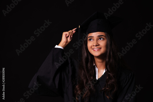 Junge Frau feiert den Abschluss ihrer Ausbildung, Portrait vor schwarzem Hintergrund mit copy space 