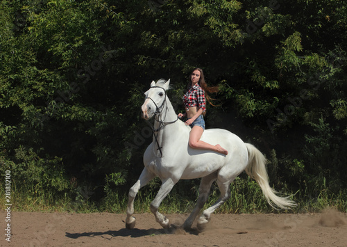 Beautiful cowgirl bareback ride her horse in woods glade at sunset