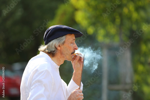 Mężczyzna odpala papierosa od metalowego pręta w parku.