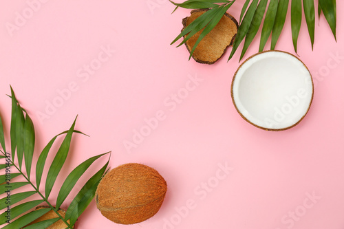 Fresh coconuts and palm leaves on pink background, flat lay. Space for text