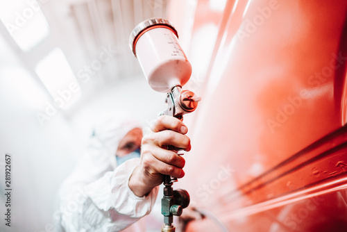 close up of male holding spray gun and painting a car