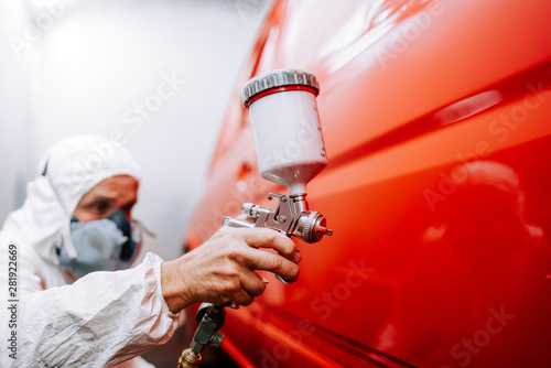 mechanic worker painting a car in a special painting box, wearing a full body costume and protection gear