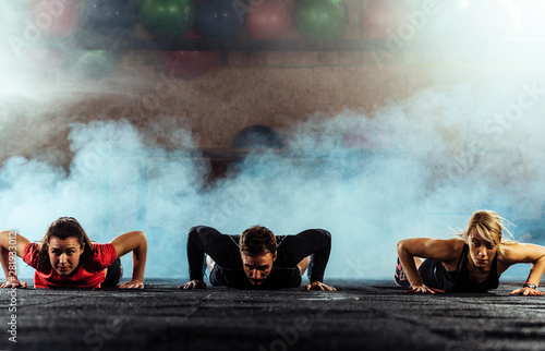 Three bodybuilders doing pushups in gym center