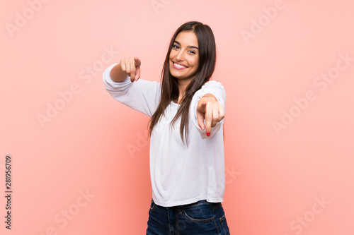 Young woman over isolated pink background points finger at you while smiling