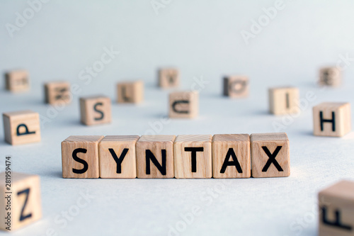 syntax - word from wooden blocks with letters, grammatical arrangement concept, random letters around, top view on wooden background