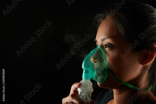 Close up view of woman using inhalation mask