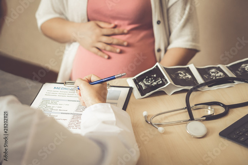 Happy pregnant woman visit gynecologist doctor at hospital or medical clinic for pregnancy consultant. Doctor examine pregnant belly for baby and mother healthcare check up. Gynecology concept.