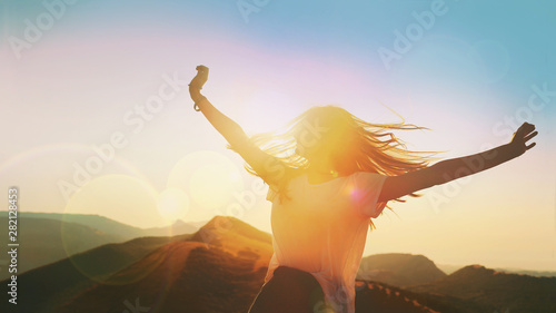 Girl on a background of mountains joyful spread her arms dancing at a height
