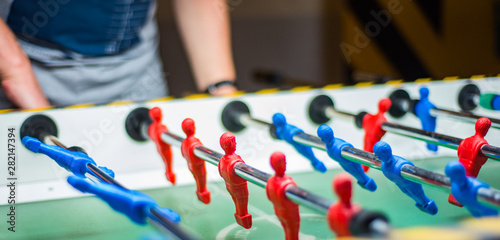 A man plays table football. Detail of man's hands playing the kicker
