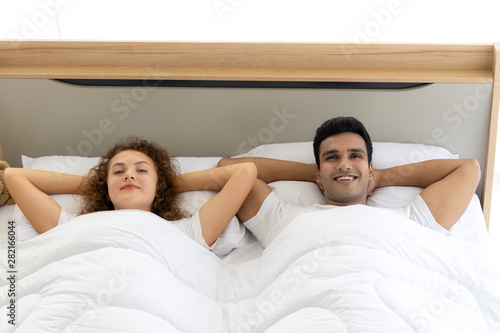 Lovely couple in duvet lying on the bed in bedroom