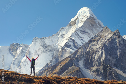 Szczęśliwy kobieta podróżnik wycieczkuje w himalajach z Ama Dablam góry tłem z plecakiem.