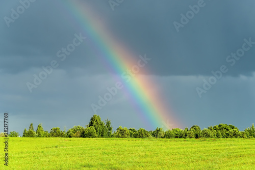 Rural landscape with rainbow in the sky after the rain.