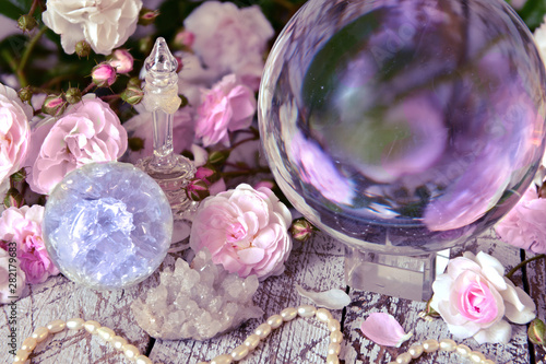 Still life with magic crystal ball, pink roses and necklace.