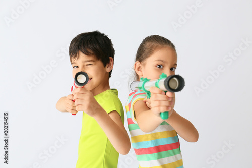 Cute little children with ball guns on light background