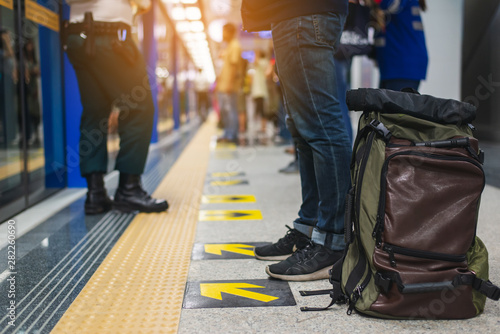 Close up photo of male waiting subway train on platform. Handsome man in black sneakers and jeans with backpack in hand standing on station. Modern citizen of big city. Lifestyle concept.