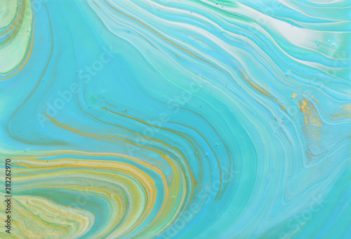 photography of abstract marbleized effect background. Blue, gold and turquoise creative colors. Beautiful paint.