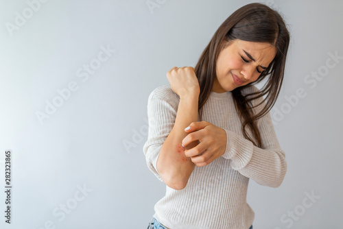 Women scratch the itch with hand , Concept with Healthcare And Medicine. Woman scratching arm on grey background. Allergy symptoms. Woman scratching her arm.