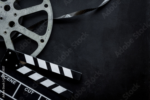 Go to the cinema with film type and clapperboard on black background top view mock up