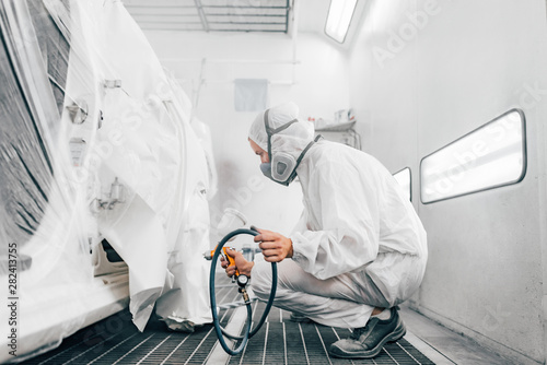 Professional car painting procedure at paint booth.