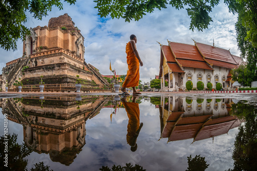 CHIANG MAI , THAILAND- AUGUST 2, 2019 : Novice is walking to study against Pagoda and reflection at Wat Chedi Luang Temple in Chiang mai, Thailand.