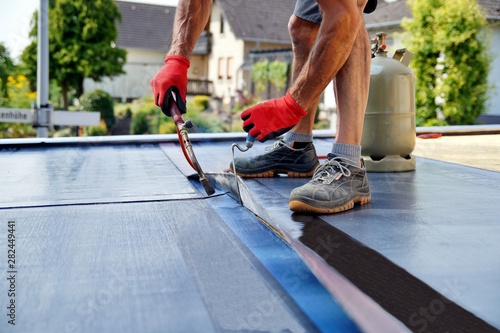 Flat roof installation with propane blowtorch during construction works with roofing felt. Heating and melting bitumen roofing felt. Roofing felt. Roofer working. Roofer working tool. Waterproofing