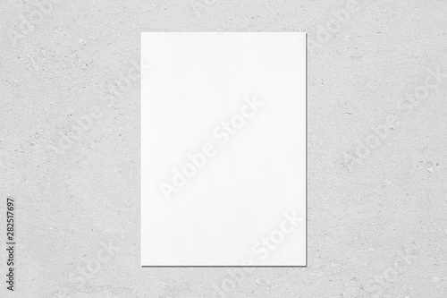 Empty white vertical rectangle poster mockup with soft shadow on neutral light grey concrete wall background. Flat lay, top view