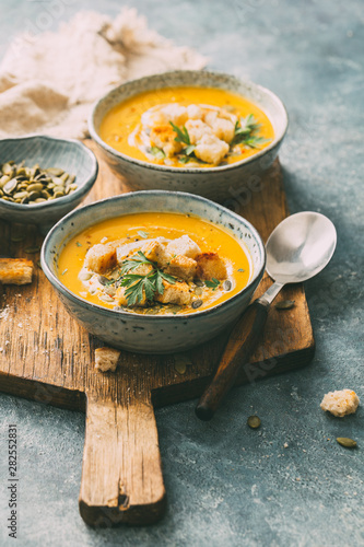 Two bowls of warm pumpkin soup with croutons and spices. Autumn food.