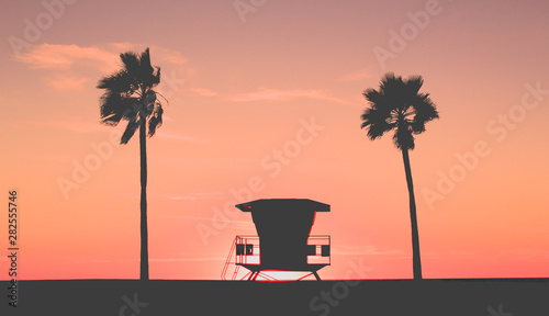 Beach Sunset with lifeguard tower, coastline and palm trees, USA.