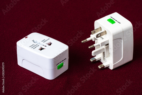 Close up of universal electric socket plug adapters used for travel. Used to connect to different electrical outlets worldwide. Electric adapter isolated on dark background.